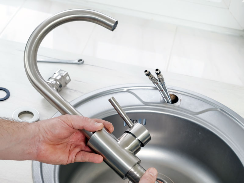 TAPS plumber installing a modern kitchen faucet.