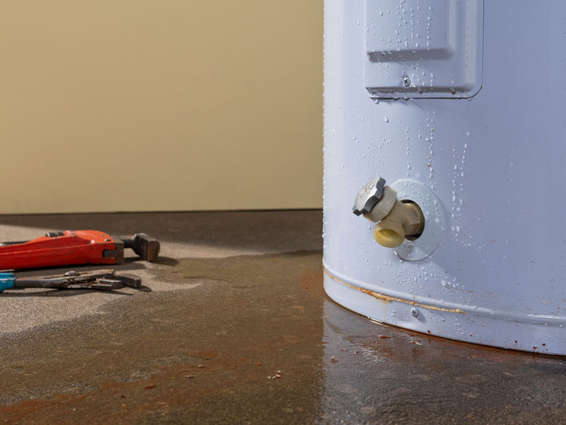 Leaking water heater tank with visible water pooling in Houston TX home